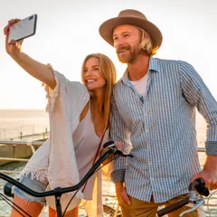 Un couple fait un selfie avec ses vélos de location au bord de la mer